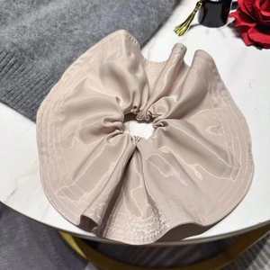 Detail of elegant beige satin scrunchie on marble background with red rose