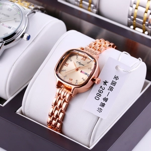 Macro detail of rose gold tonneau watch with rhinestone markers and dual date display