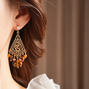 Ethnic gold drop earrings with hollow geometric design and amber beads on a model