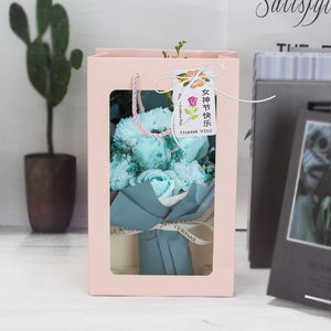 Detailed view of blue soap flower bouquet in a pink gift box with festive tag