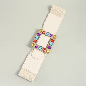Detail of a beige elastic waist belt featuring a large square buckle with multi-color gems