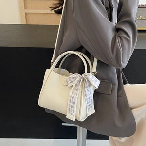 White lychee pattern bucket bag with a blue plaid scarf shown on a grey suit model