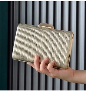 Detail of elegant gold evening clutch bag with vertical pleated texture and metallic clasp