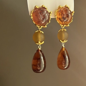 Macro view of vintage resin drop earrings with amber bead and golden floral settings