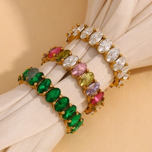 Detail of three gold rings with oval cubic zirconia in white, green, and multicolor