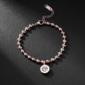 Detail of rose gold beaded bracelet with Roman numeral pendant and sparkling zircon