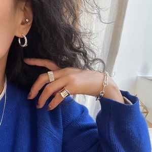 Close-up of 925 sterling silver woven earrings and minimalist rings on a female model