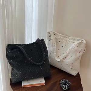Vista lifestyle di borse tote intrecciate con pois colorati su tavolo in legno