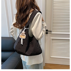 Detail of black large canvas tote bag with biscuit pendant charm on a female model