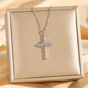Silver cross necklace with interlocking hearts and pave cubic zirconia on silk background