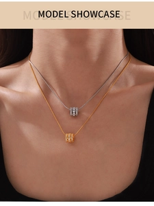 Detail of gold and silver cylinder pendants with cubic zirconia on snake chain necklace