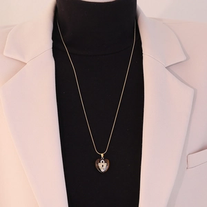 Detail of heart-shaped tiger eye stone pendant on gold chain necklace worn on model
