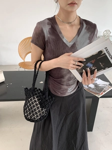 Detail of coffee gray tie-dye V-neck T-shirt paired with a black woven bucket bag