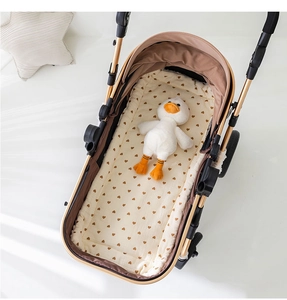 Close-up of beige cotton stroller cushion with brown heart patterns in a cozy setting