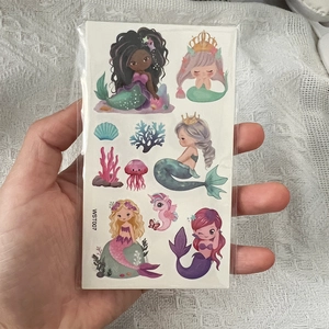 Detail shot of waterproof mermaid tattoo stickers featuring seahorse and coral designs
