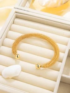 Detail of 18K gold-plated spring spiral bangle in elegant velvet jewelry box