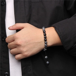 Macro detail of snowflake obsidian stone beads on an adjustable hand-woven bracelet
