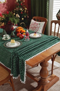 Close-up of green plaid Christmas tablecloth with white snowflake patterns and pompom fringe