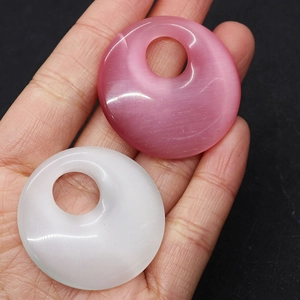 Detailed view of pink and white cat eye stone donut pendants held in hand