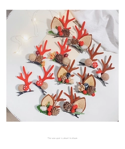 Flat lay of 10 Christmas antler hair clips with pine cones and berries on a white table