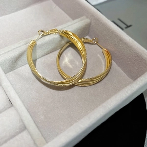 Gros plan de créoles dorées torsadées au fini mat texturé dans un écrin à bijoux en velours