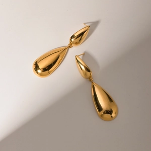 Macro shot of polished gold-plated double teardrop earrings with smooth mirror finish