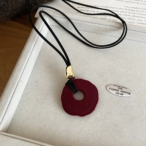 Detail of red flocked resin ring pendant with golden hardware and black cord necklace