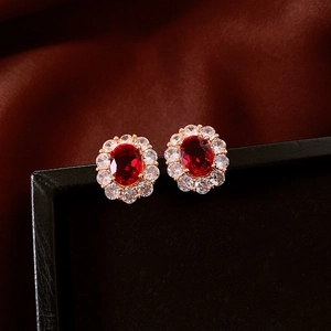 Macro detail of 18K gold plated oval earrings with red gems and sparkling halo studs