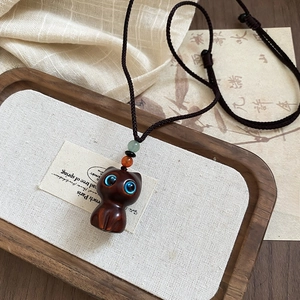 Macro shot of wooden cat pendant necklace with bright blue eyes on braided rope