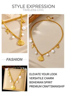 Detail of gold chain necklace featuring shell, dolphin and pearl charms on sandy background