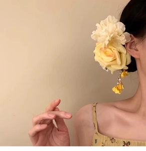 Detail of fabric rose and pearl tassels on a yellow floral hair clip for women