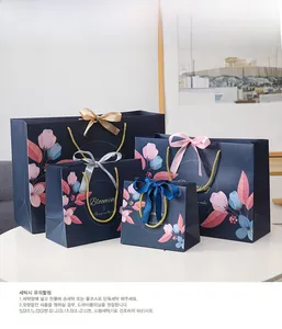 Floral paper gift bags in four sizes with elegant gold rope handles and satin bows