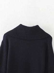 Detail of dark blue knit sweater showing ribbed high collar and thick fabric texture