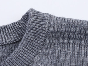 Détail du pull en maille grise avec une encolure ronde et un tissage de précision