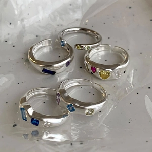 Colorful zircon heart rings set with irregular silver bands on a ceramic tray