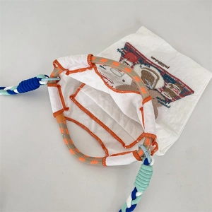 Détail du sac en toile ours brodé avec anses tissées colorées et surpiqûres oranges