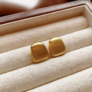 Detailed macro of irregular teardrop geometric earrings with warm gold brushed metal finish