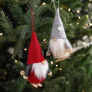 Handmade felt Christmas gnome ornaments with wooden skis hanging on a festive tree branch