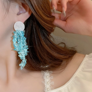 Detail of long tassel earrings with white shell studs and blue beaded stone fringe