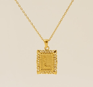 Gros plan du pendentif lettre L dorée avec cadre ajouré et texture rayonnante