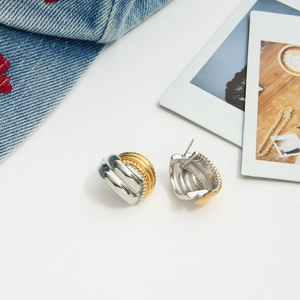 Close-up of two-tone 18K gold and silver chunky textured hoop earrings with a denim jacket