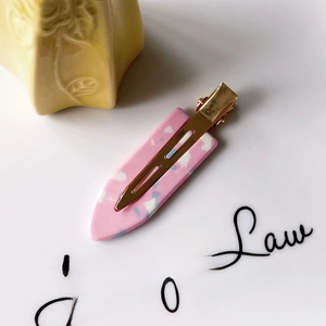 Detailed macro of a pink terrazzo acetate duckbill hair clip with golden metal clip