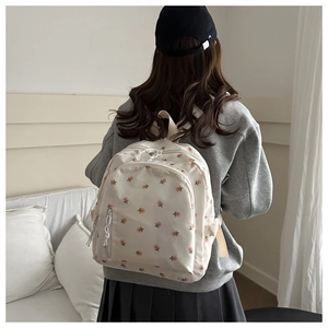 Close-up of floral print nylon backpack featuring pink blossoms and white drawstring detail