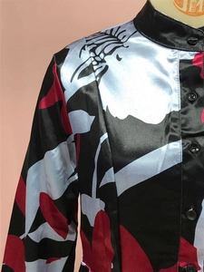 Close-up of stand-up collar and black buttons on a satin floral print dress