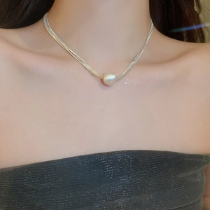 Detail of silver layered snake chain necklace featuring a large single pearl pendant