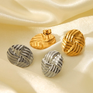 Close-up of woven texture on 18K gold and silver oval stud earrings on yellow silk