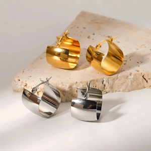 Polished gold and silver chunky hoop earrings set on minimalist stone display
