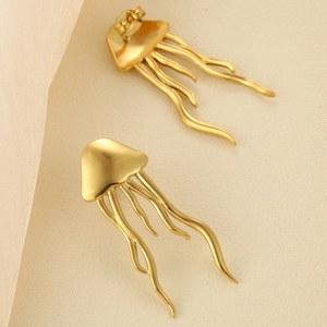 Detailed view of golden jellyfish earrings featuring a unique ocean design on white leather