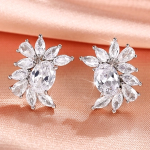 Macro detail of silver flower earrings with radiant zircon clusters on pink silk