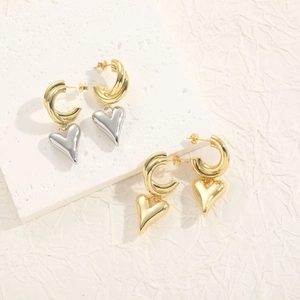 Minimalist gold C-shaped hoop earrings with 3D heart charms on a white stone base